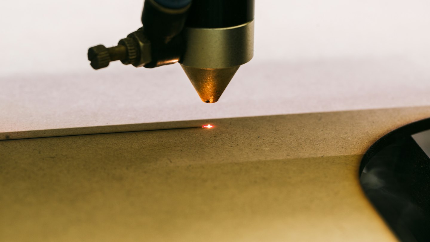 Raggio di un'incisore laser che brucia un disegno su legno.