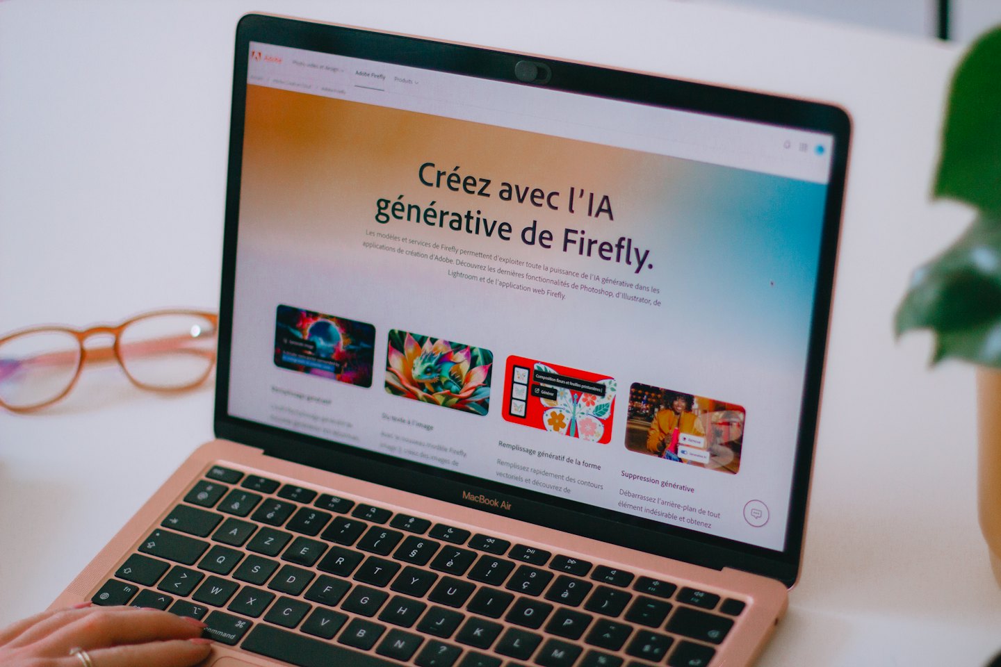 Mano che digita su un laptop color oro rosa che mostra una pagina web sull'IA.