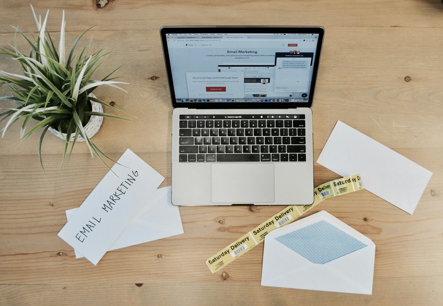 Computer portatile aperto su un sito web di email marketing su una scrivania di legno.